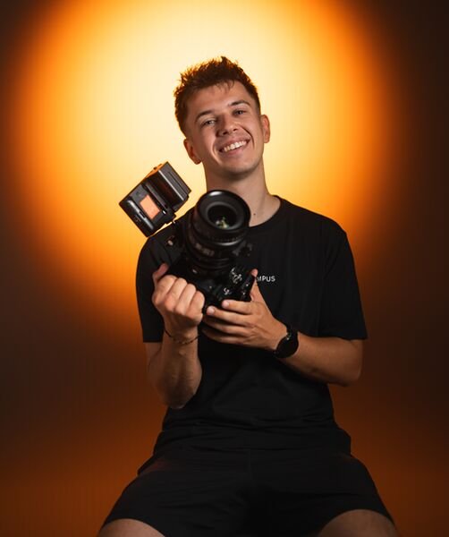 Florian Haller mit Kamera vor orangefarbenem Scheinwerferlicht